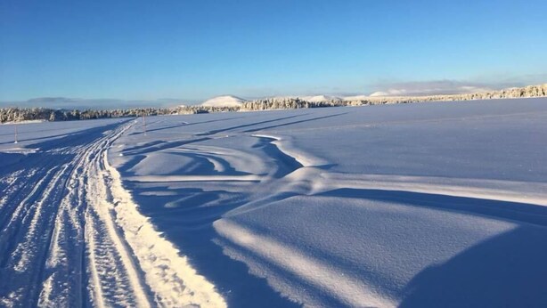 A vast, open snowy landscape with tire tracks leading into the distance and a clear blue sky above. - Sonfjällsgården Wärdshus & Hotell (Hede)