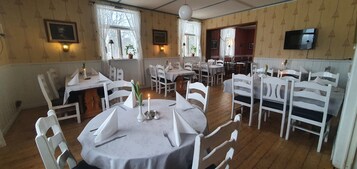 Un comedor con mesas redondas, sillas blancas y centros de mesa con velas.