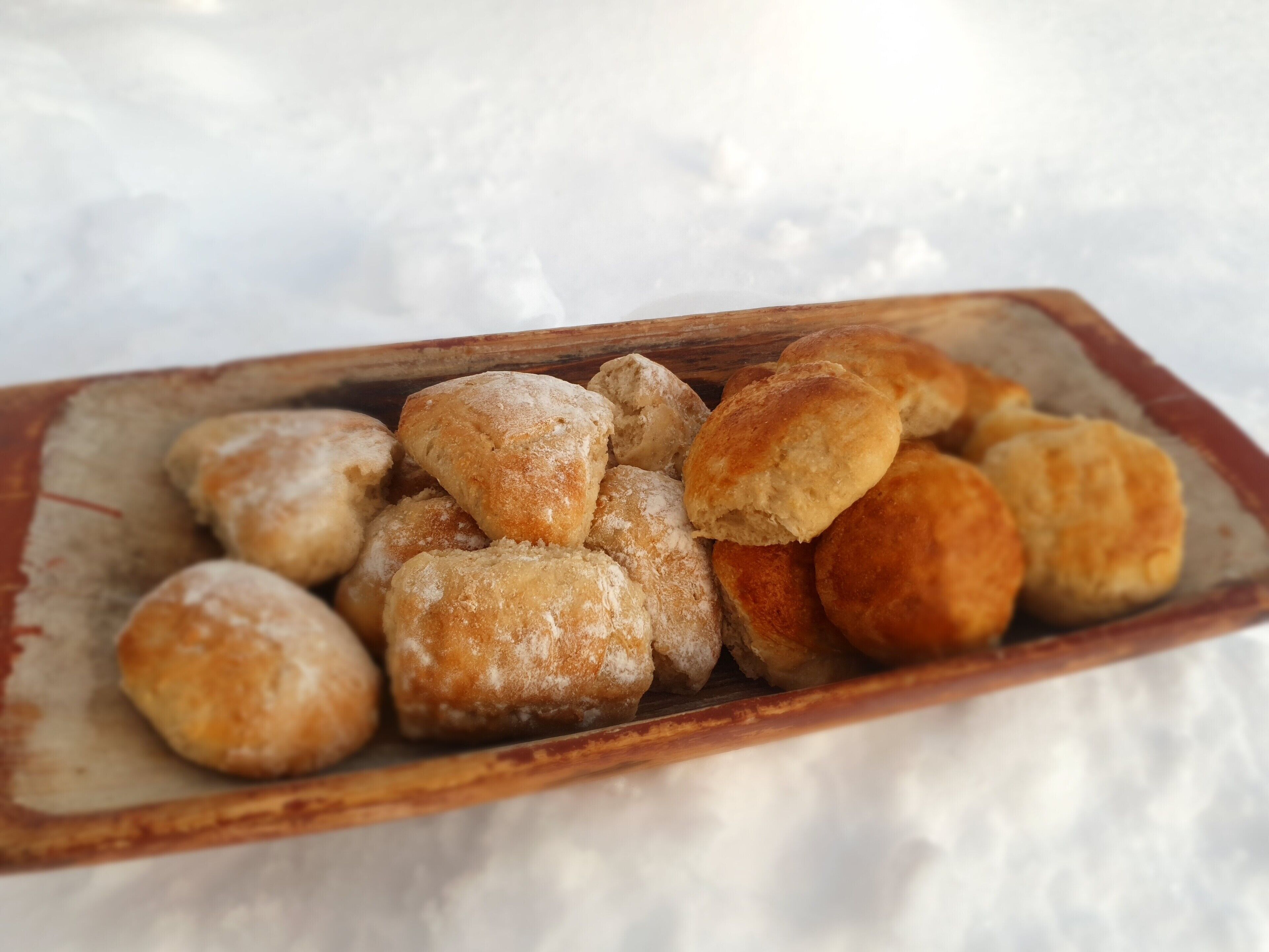 Bandeja de pasteles sobre una superficie de madera, con nieve al fondo.