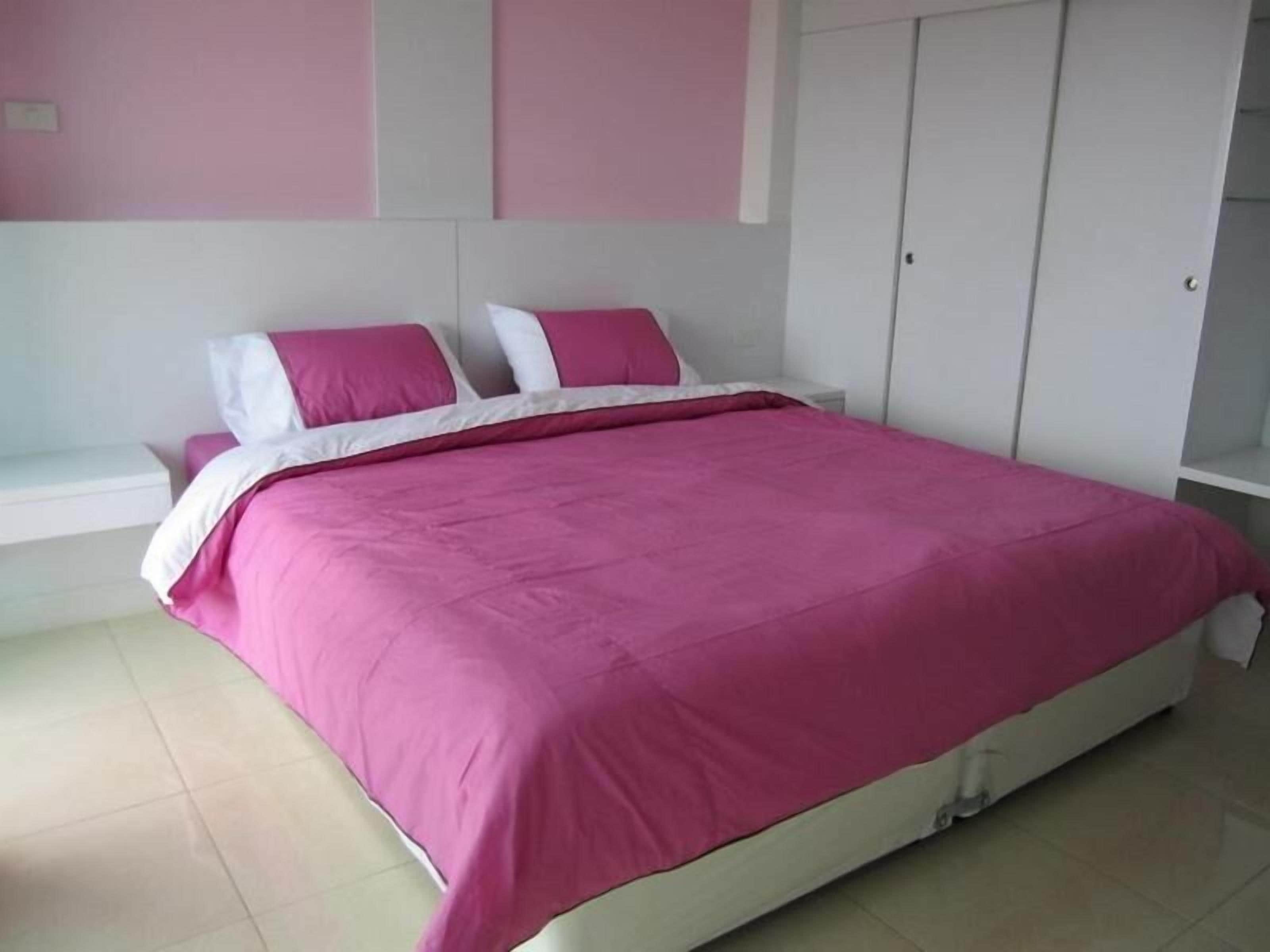 A bedroom with a bed, white nightstands, and a wardrobe.