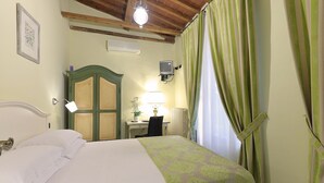 Una habitación de hotel con cama, escritorio, silla, lámpara y cortinas.