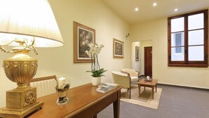 Una habitación amplia con una mesa de madera, una lámpara y obras de arte enmarcadas en las paredes.