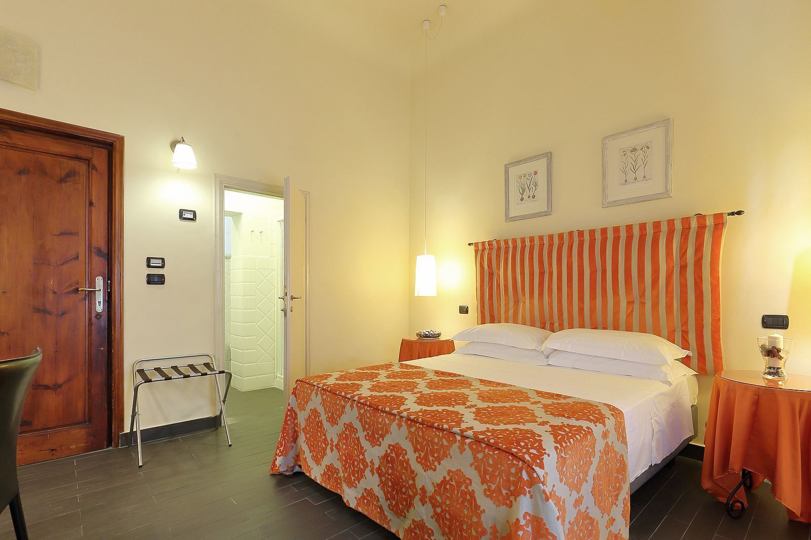 Ein Hotelzimmer mit Bett, Sessel, Schreibtisch und Tür.