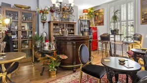 A well-lit, elegantly furnished living room with a large wooden cabinet, a red refrigerator, and a chandelier. - Mama's Inn Boutique Guest House (Nottingham)