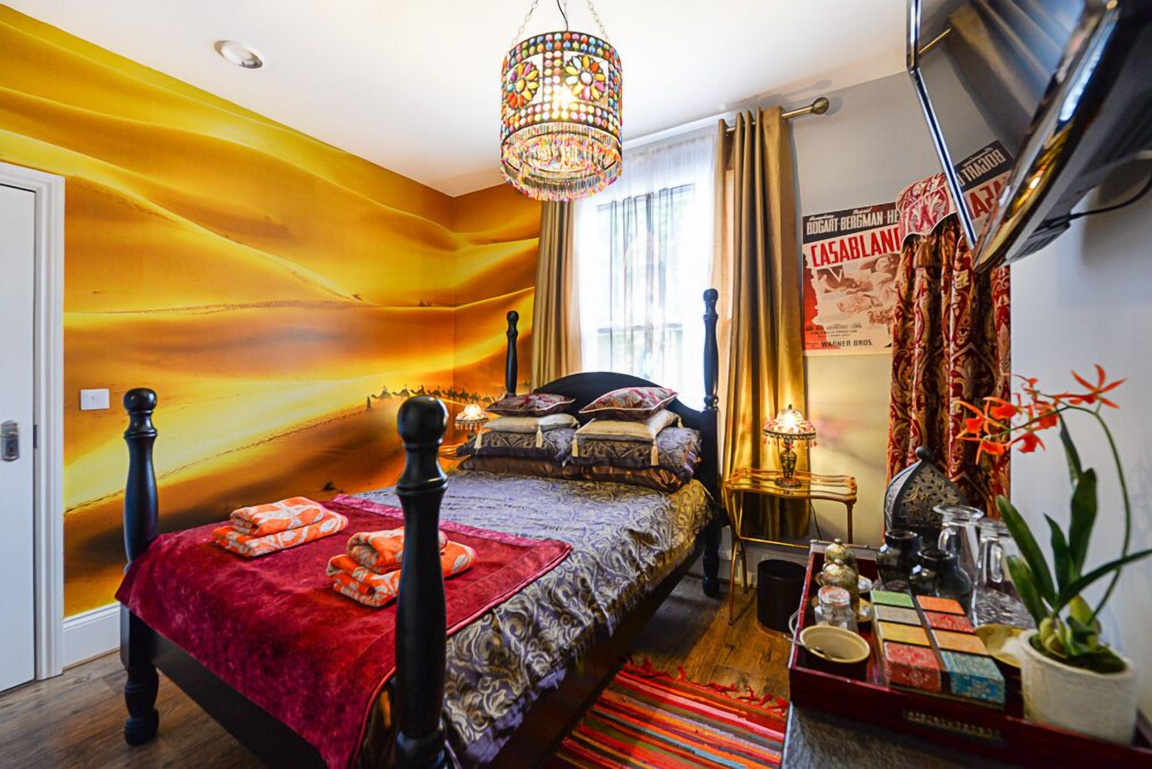 Ein Schlafzimmer mit einem Bett, einer Kandelaber, einem Nachttisch und einer Wand mit einem Poster.