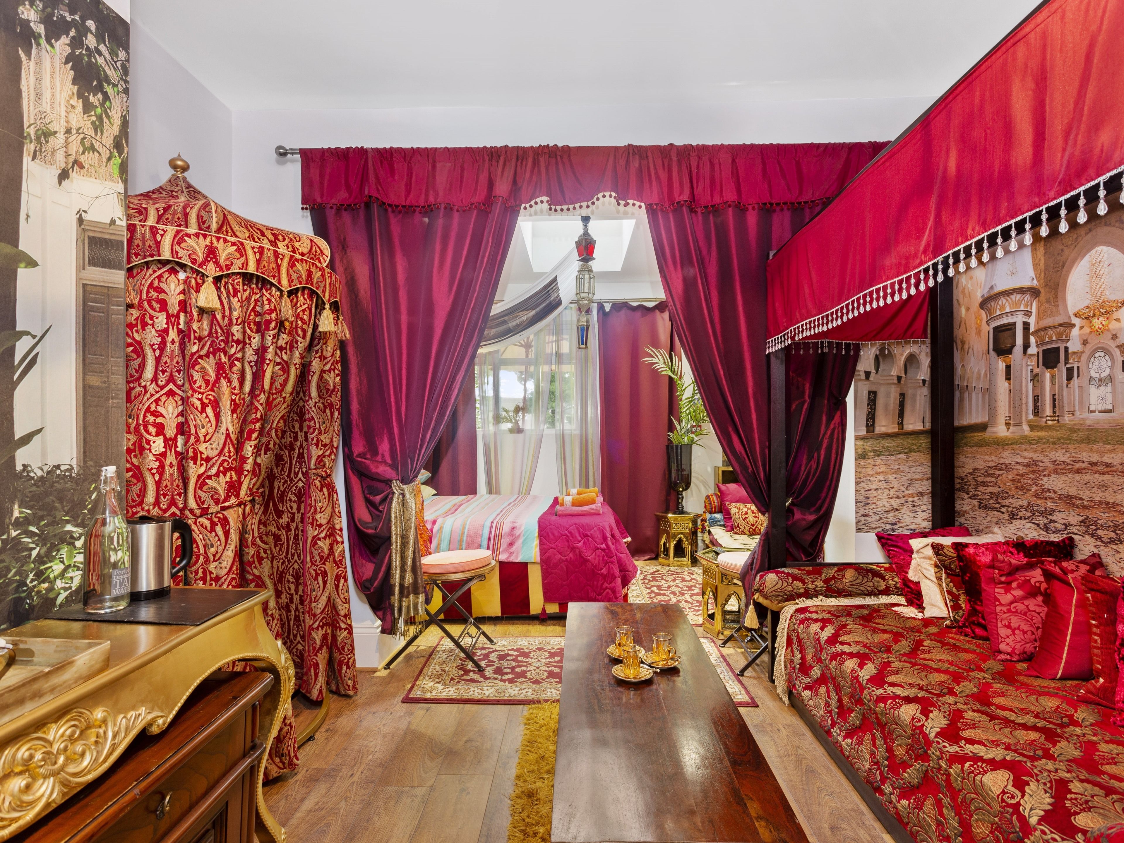 Ein luxuriöses Schlafzimmer mit einem großen Bett, einer Sitzecke und Blick auf einen Innenhof.