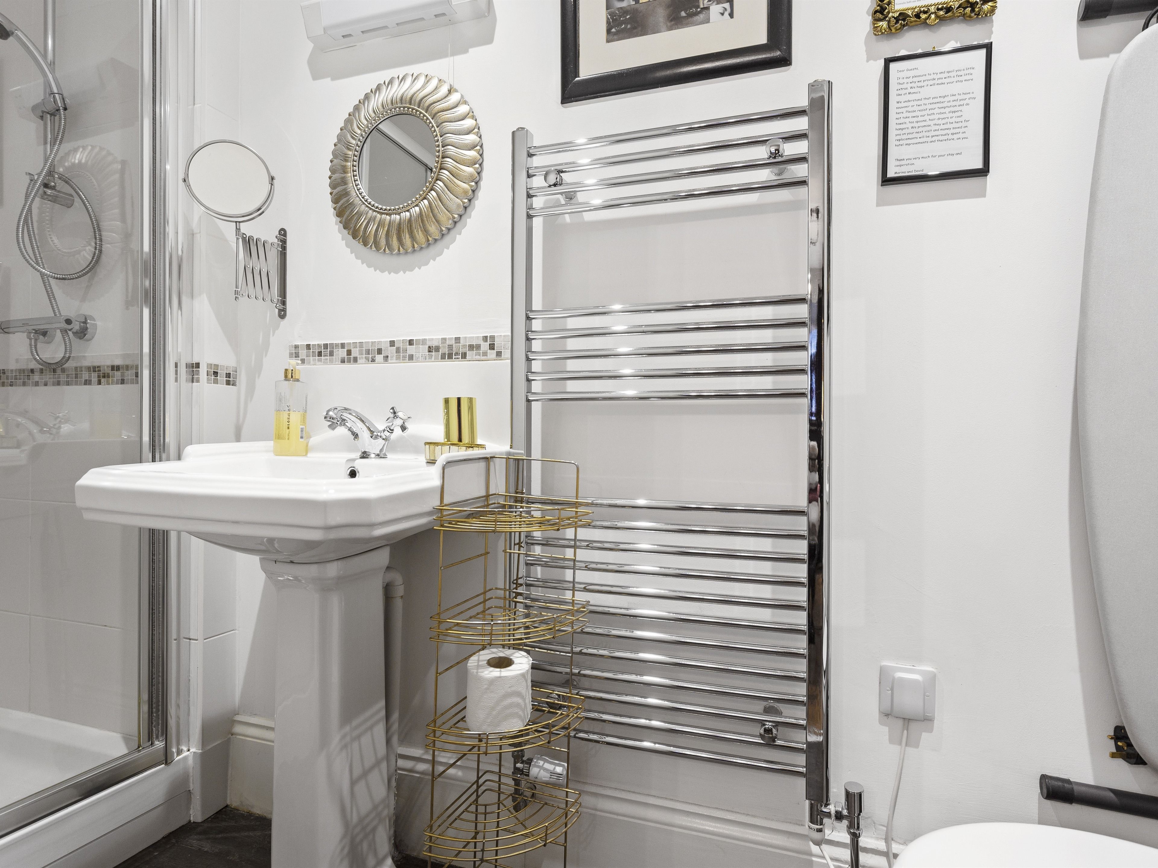 A bathroom with a white sink, a mirror, a towel rack, and a shower.