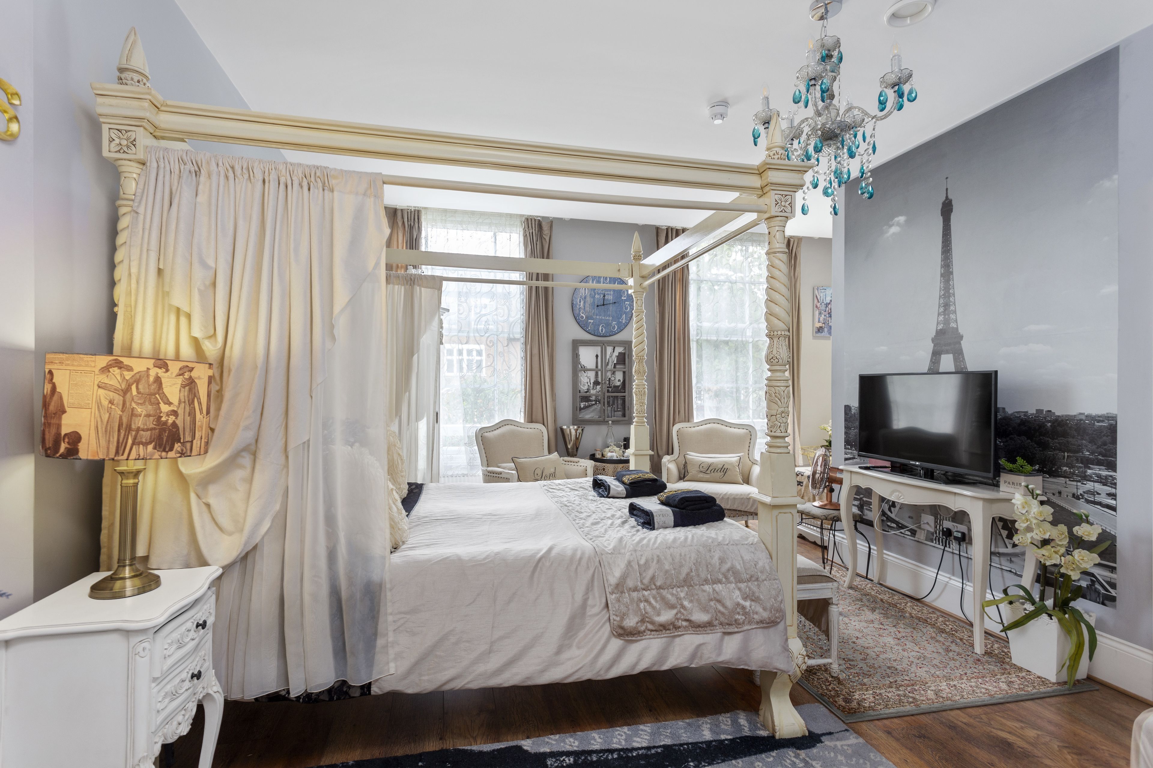 Un dormitorio con cama con dosel, televisión y vista de la Torre Eiffel en la pared.