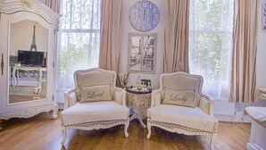 A room with two armchairs labeled "Lord" and "Lady," a round wall clock, a mirror with an Eiffel Tower reflection, and a small table with decorative items. - Mama's Inn Boutique Guest House (Nottingham)
