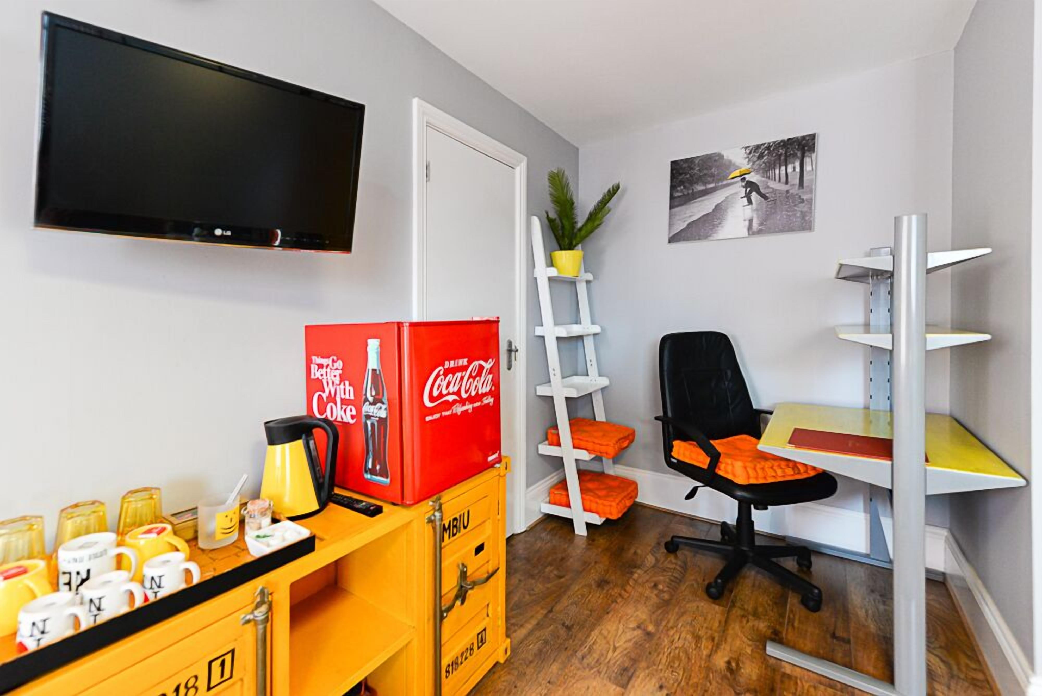 A compact office space with a flat-screen TV, a desk with a chair, a ladder, and storage boxes.