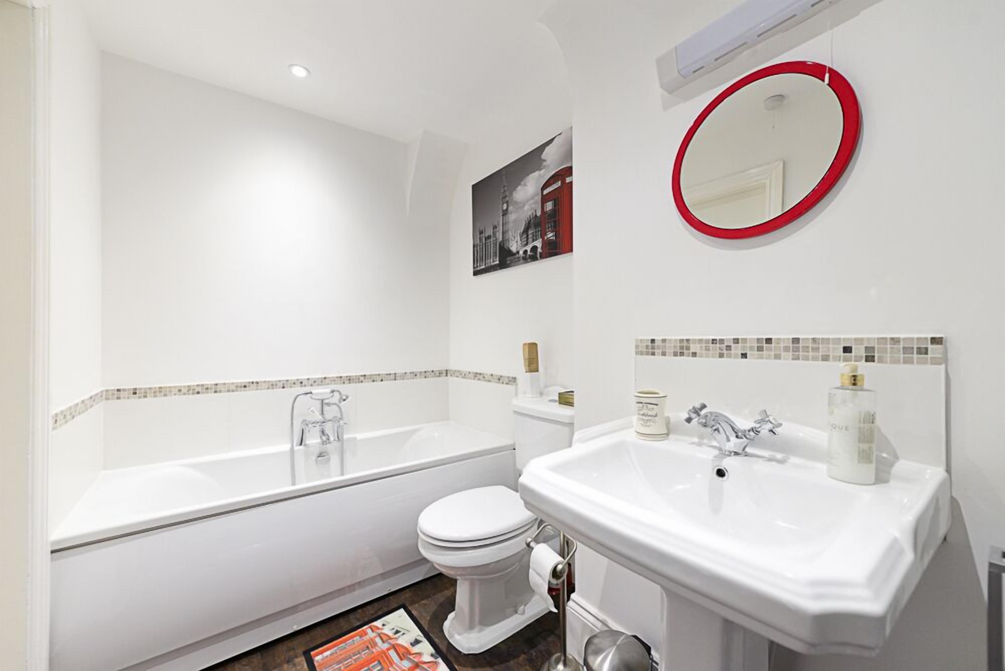 Un baño moderno con una bañera blanca, un inodoro y un lavabo.