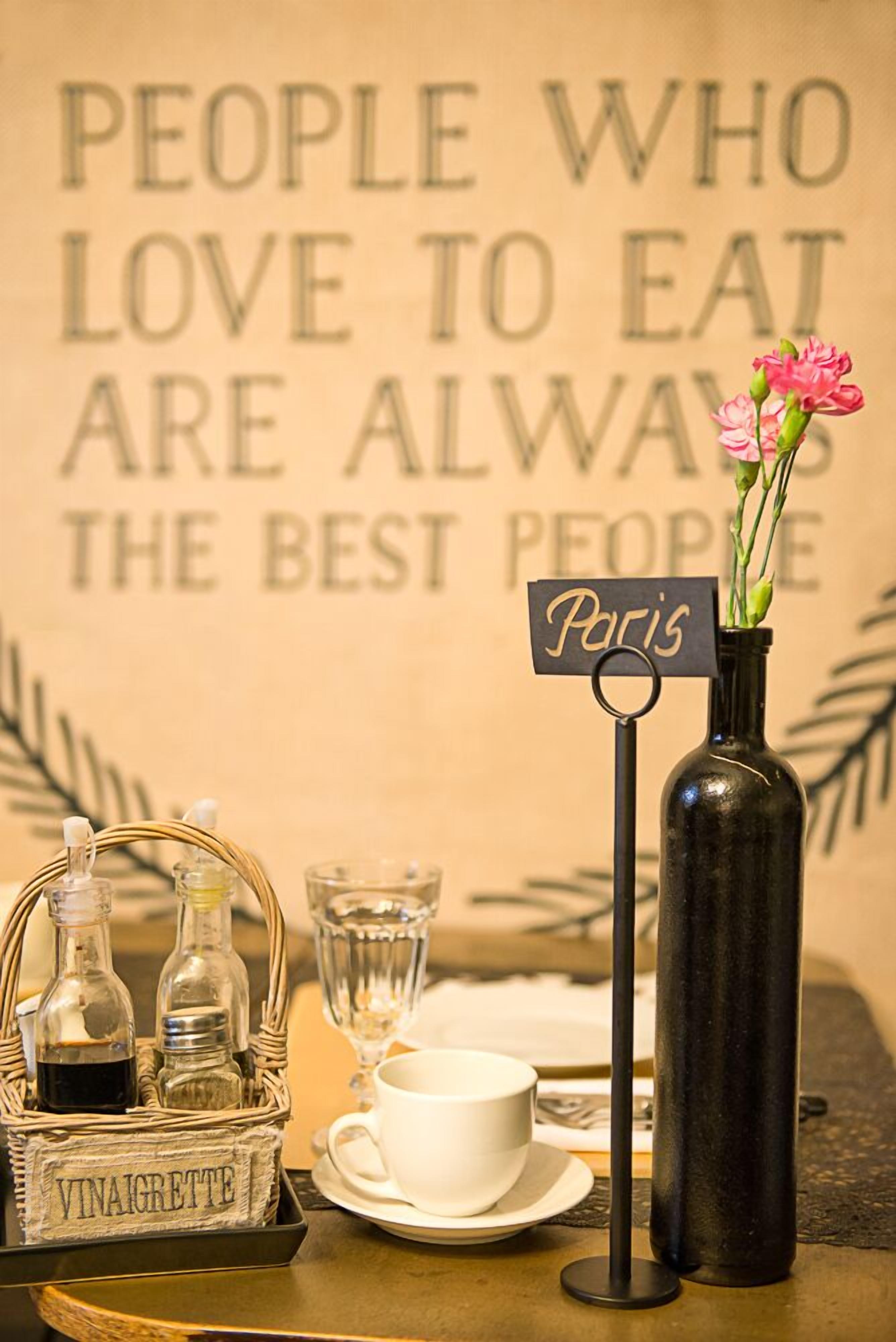 A table setting with a vase of pink flowers, a sign reading "Paris," and a basket labeled "VINAIGRETTE."