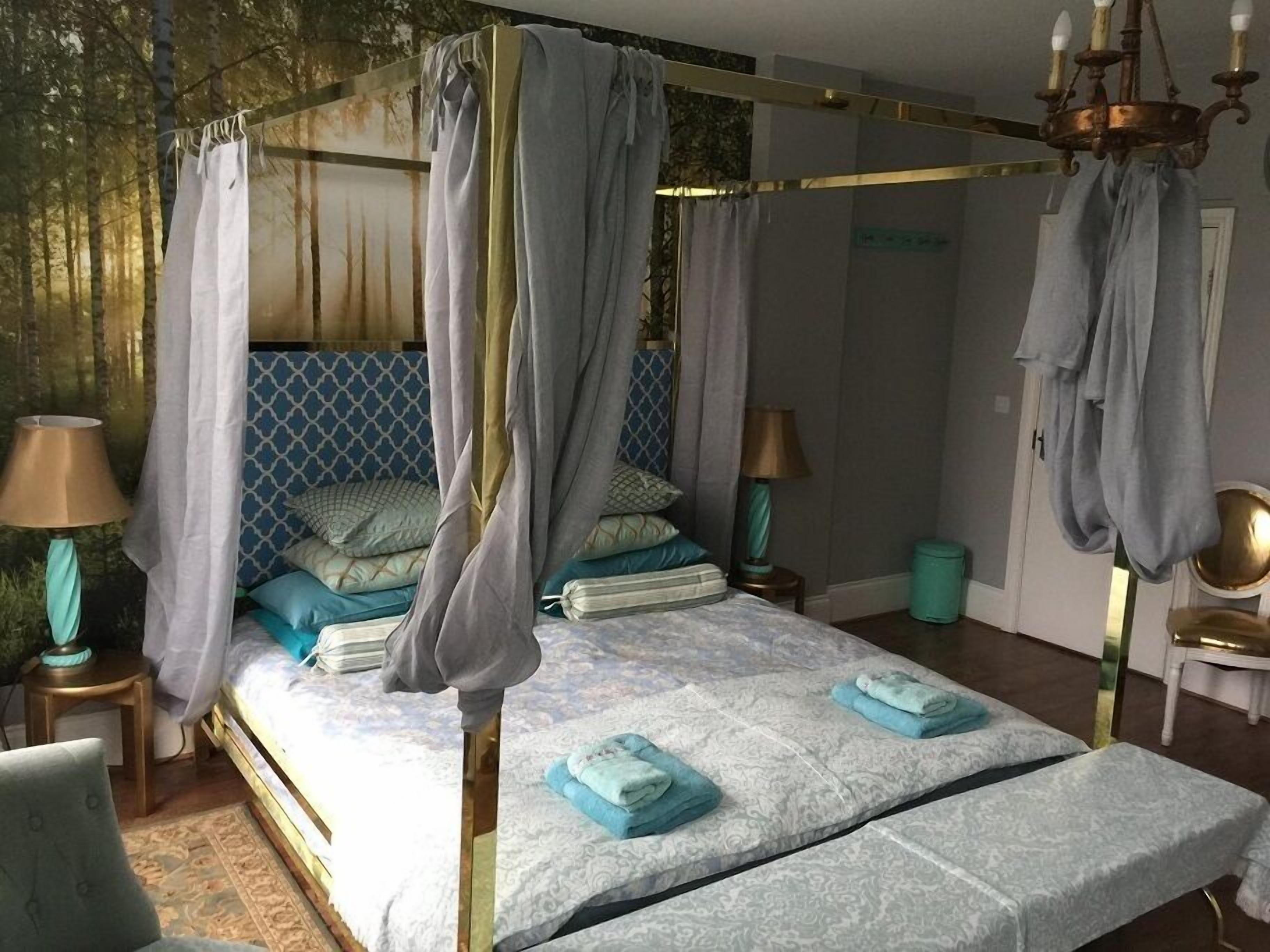 Un lit à baldaquin avec des poteaux aux quatre coins, une tête de lit décorée et deux tables de chevet avec des lampes.