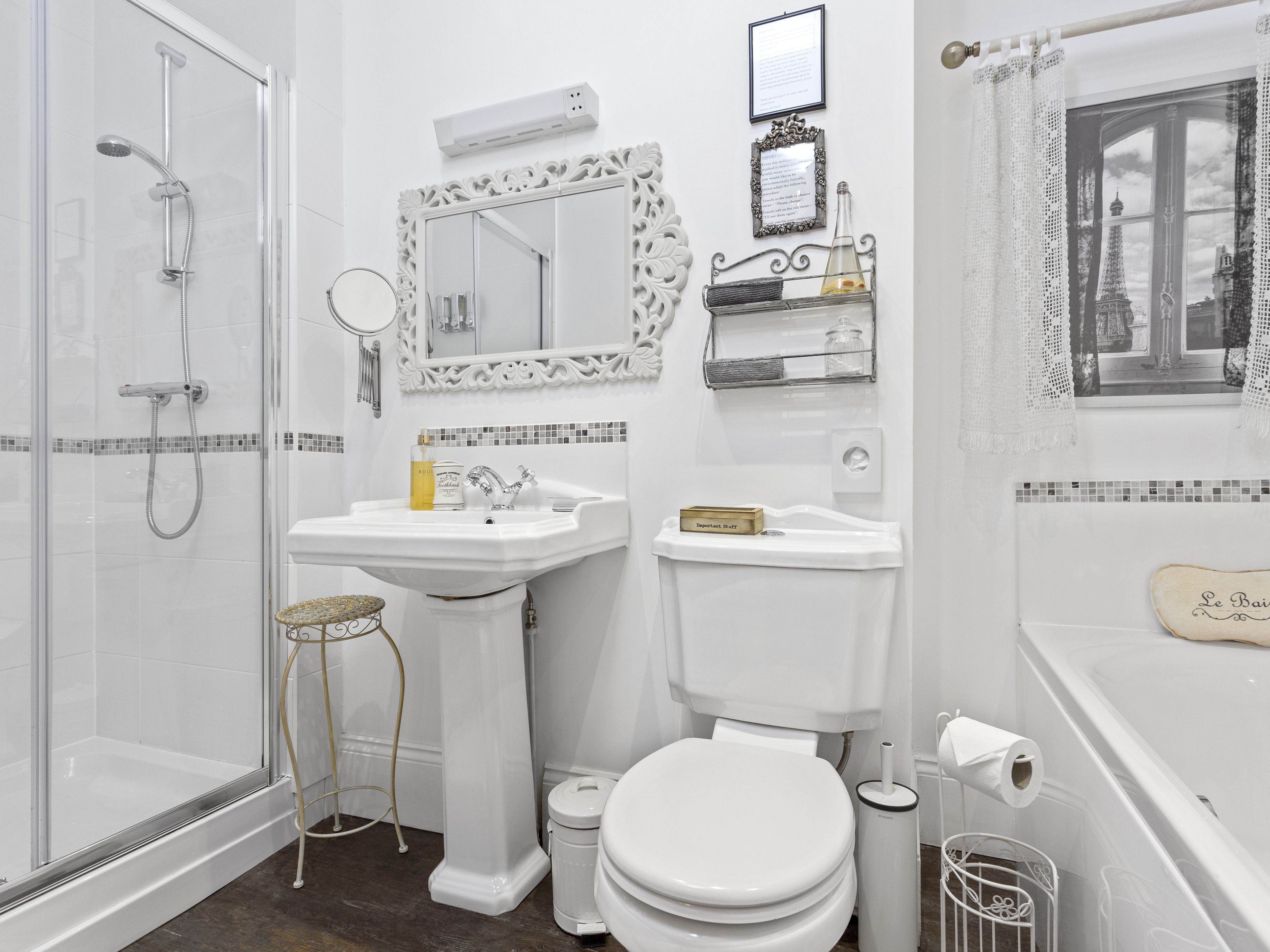 A modern bathroom with a glass-enclosed shower, a pedestal sink, a toilet, and a bathtub.