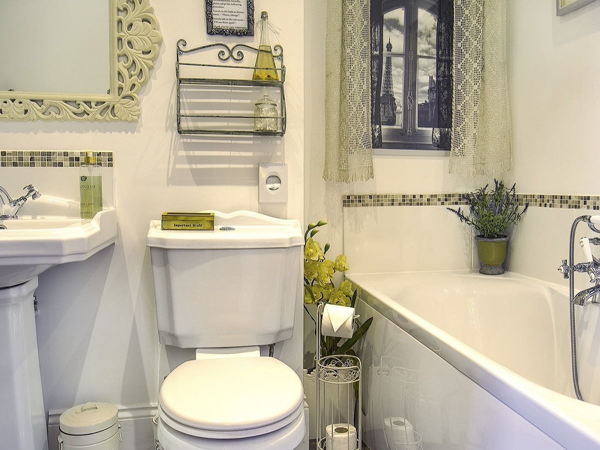 A bathroom with a toilet, sink, and bathtub. There is a window with a view of the Eiffel Tower.