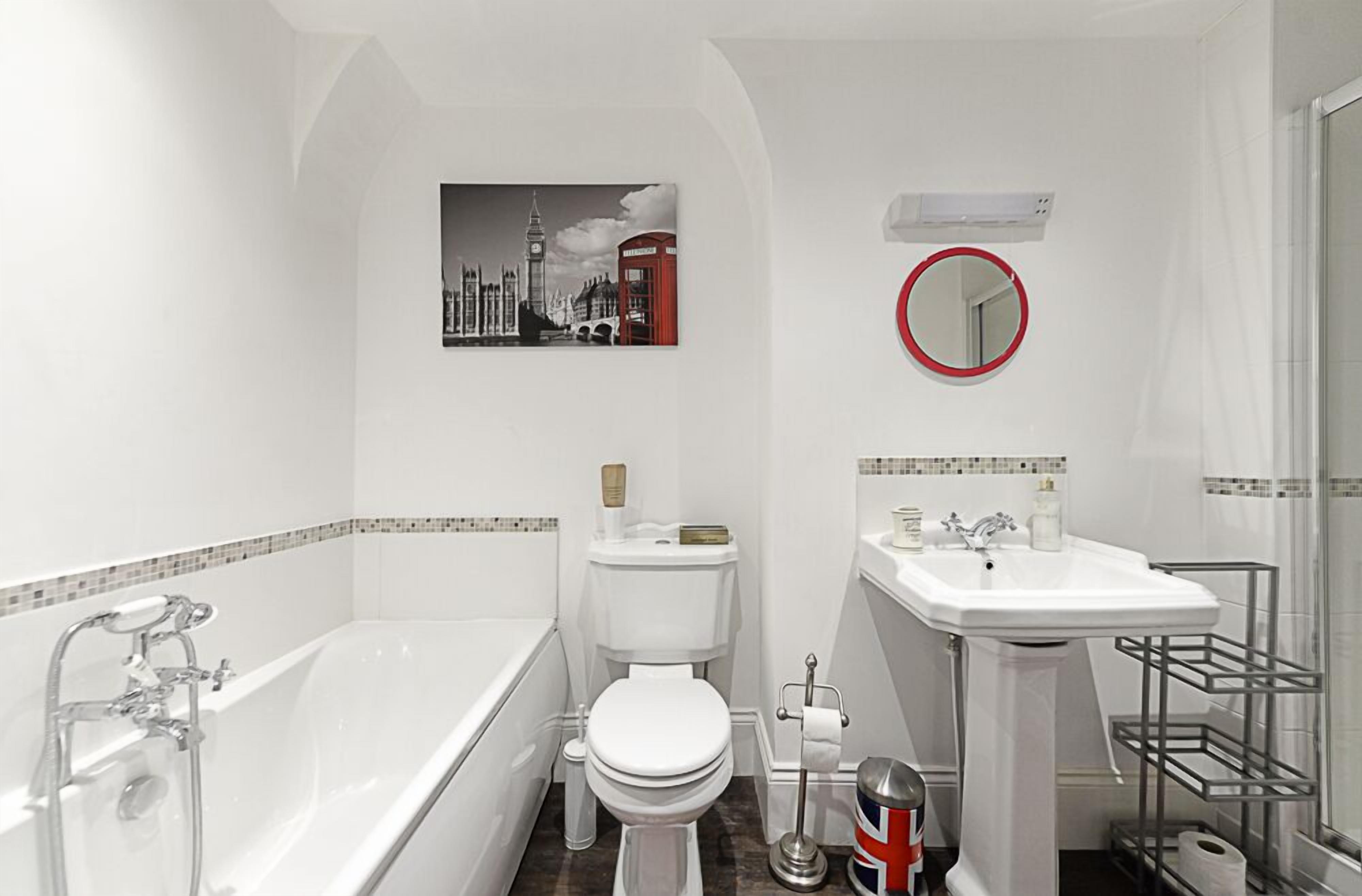 A bathroom with a bathtub, toilet, sink, and a mirror.