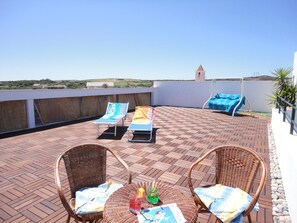 A rooftop terrace with two wicker chairs, a table with a drink, and lounge chairs with towels. - Hotel Ristorante Silvestrino (Stintino)