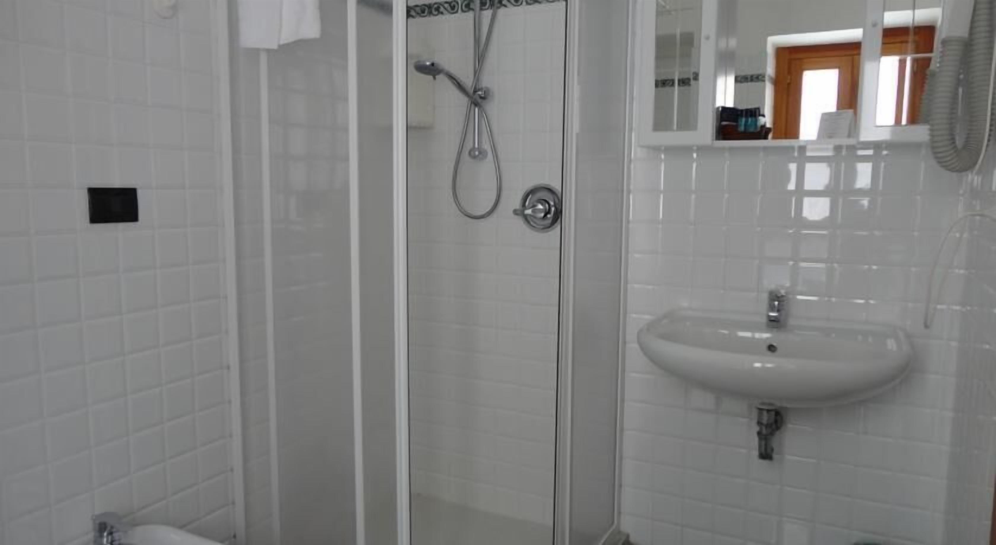 A bathroom with a glass-enclosed shower, a white sink, and a mirror above the sink.