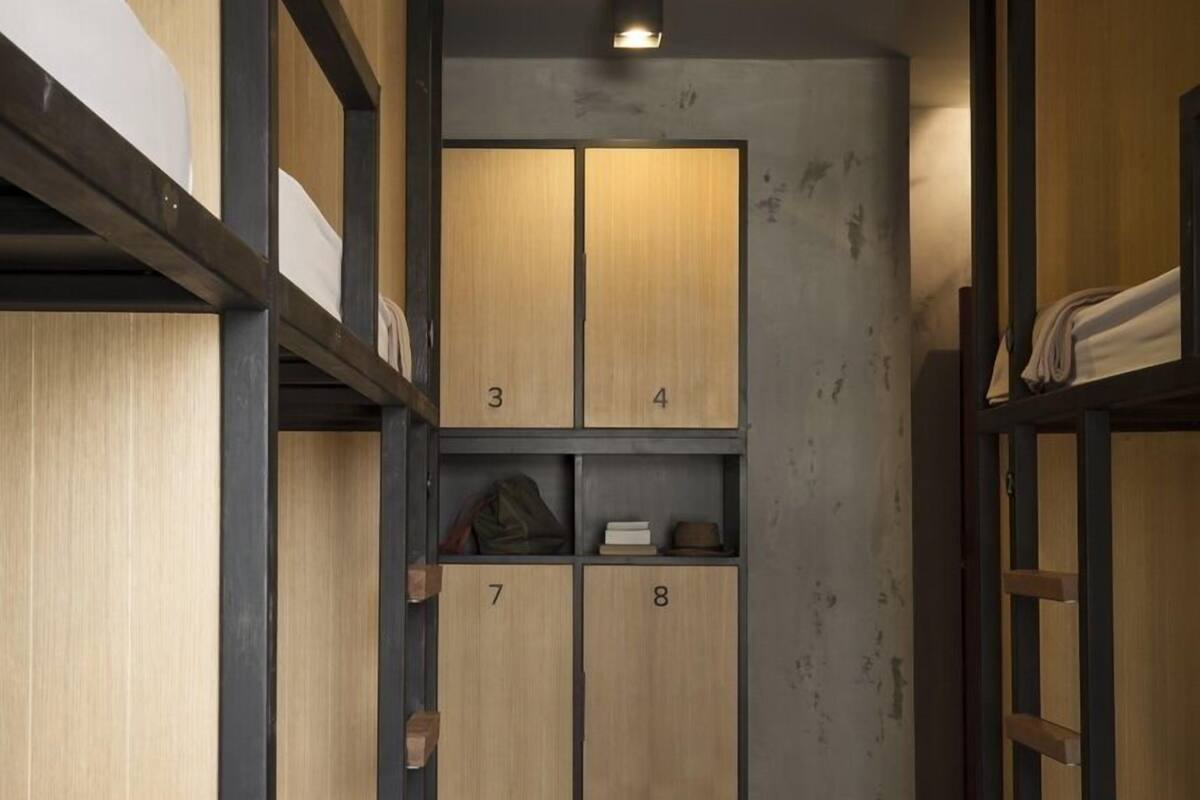 A narrow hallway with bunk beds on both sides and a central shelving unit with numbered compartments.