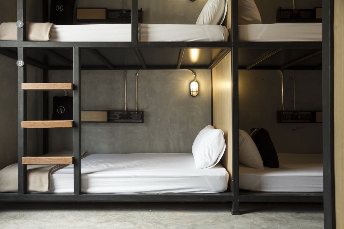 Habitación con literas, una escalera, repisa en la pared y lámpara colgante.