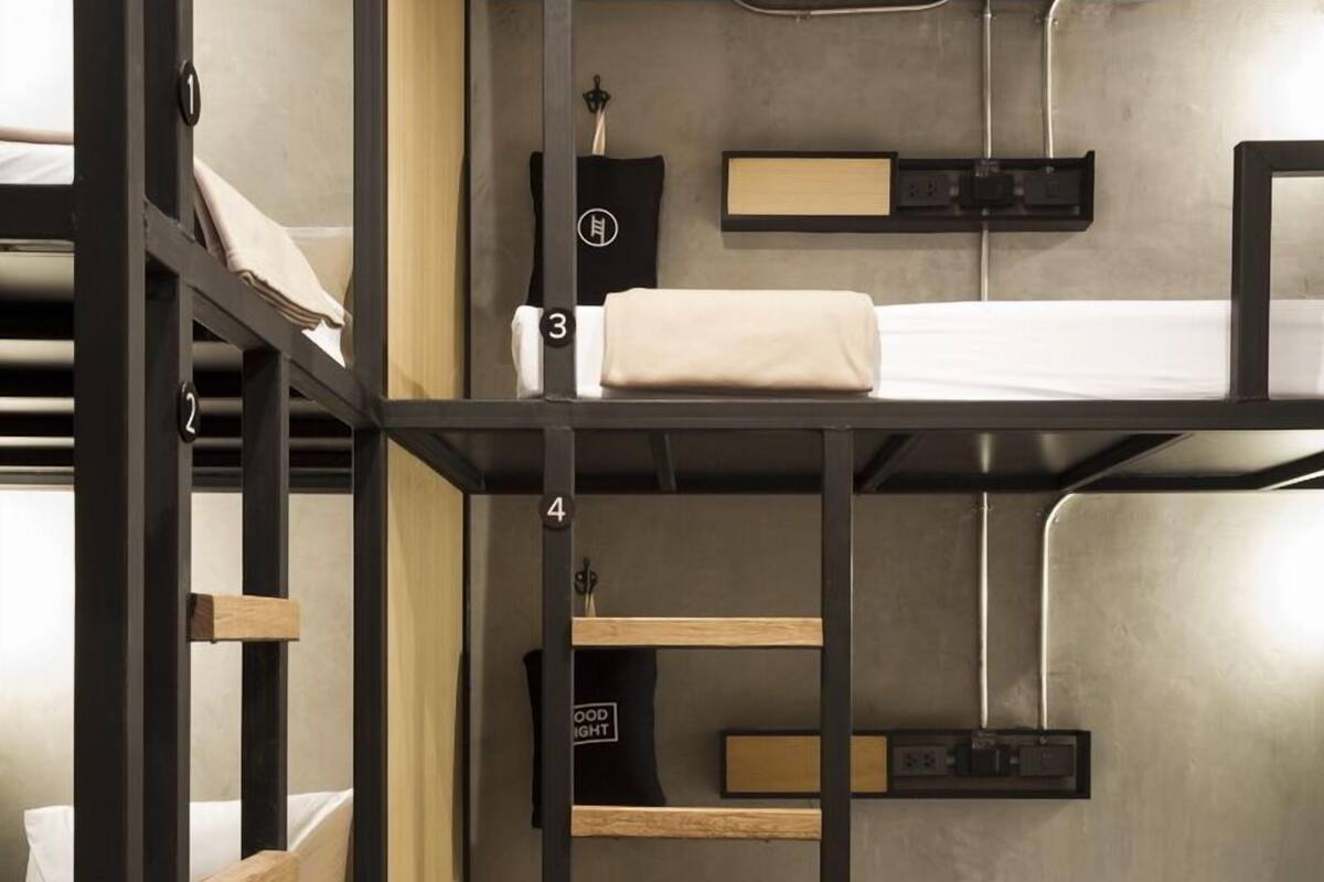 A bunk bed room with a concrete floor, metal railings, and a small shelf with a clock.