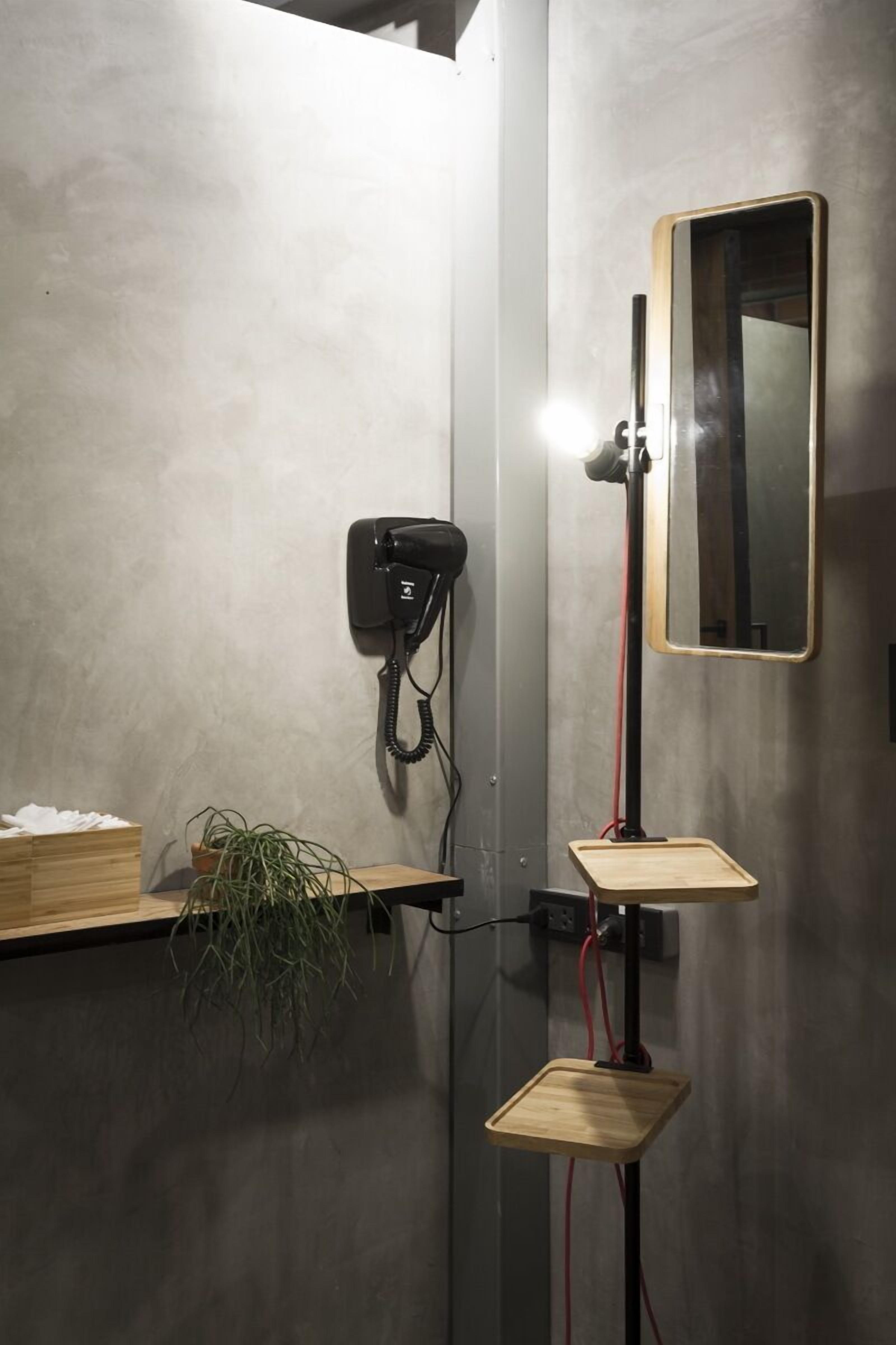 A bathroom with a wooden shelf, a potted plant, a hairdryer, and a mirror.