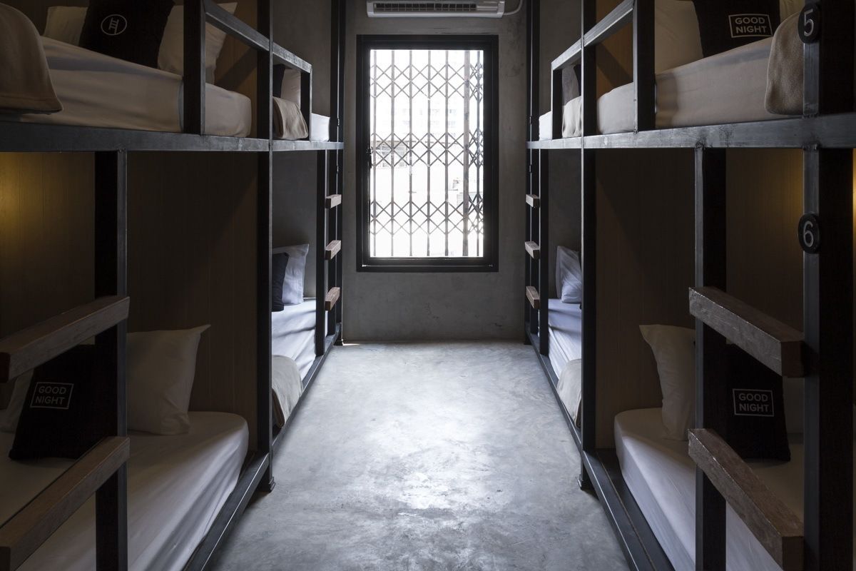 A narrow corridor with bunk beds on either side, a barred window at the end, and a sign reading "GOOD NIGHT" on each bed.