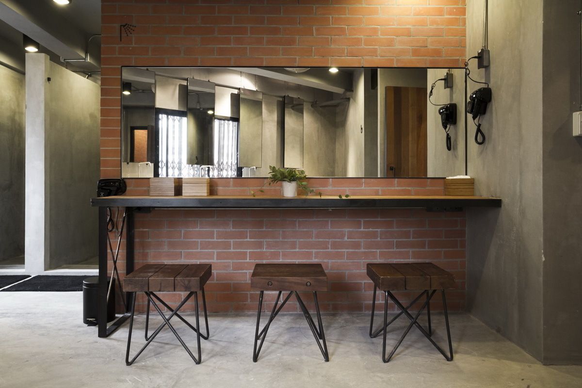 Un área de bar con pared de ladrillo, un espejo grande y tres taburetes.