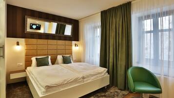 Een moderne hotelkamer met een groot bed, een groene stoel, een televisie aan de muur en een raam met gordijnen.