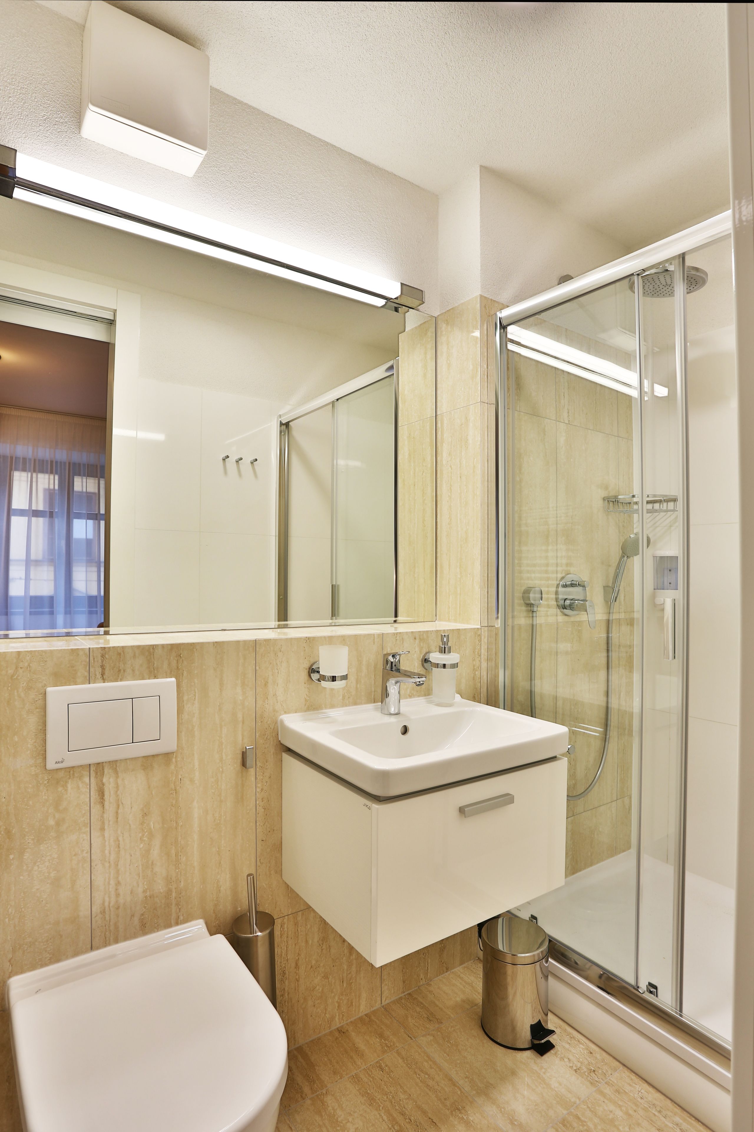 A modern bathroom with a glass-enclosed shower, a white sink, and a toilet.