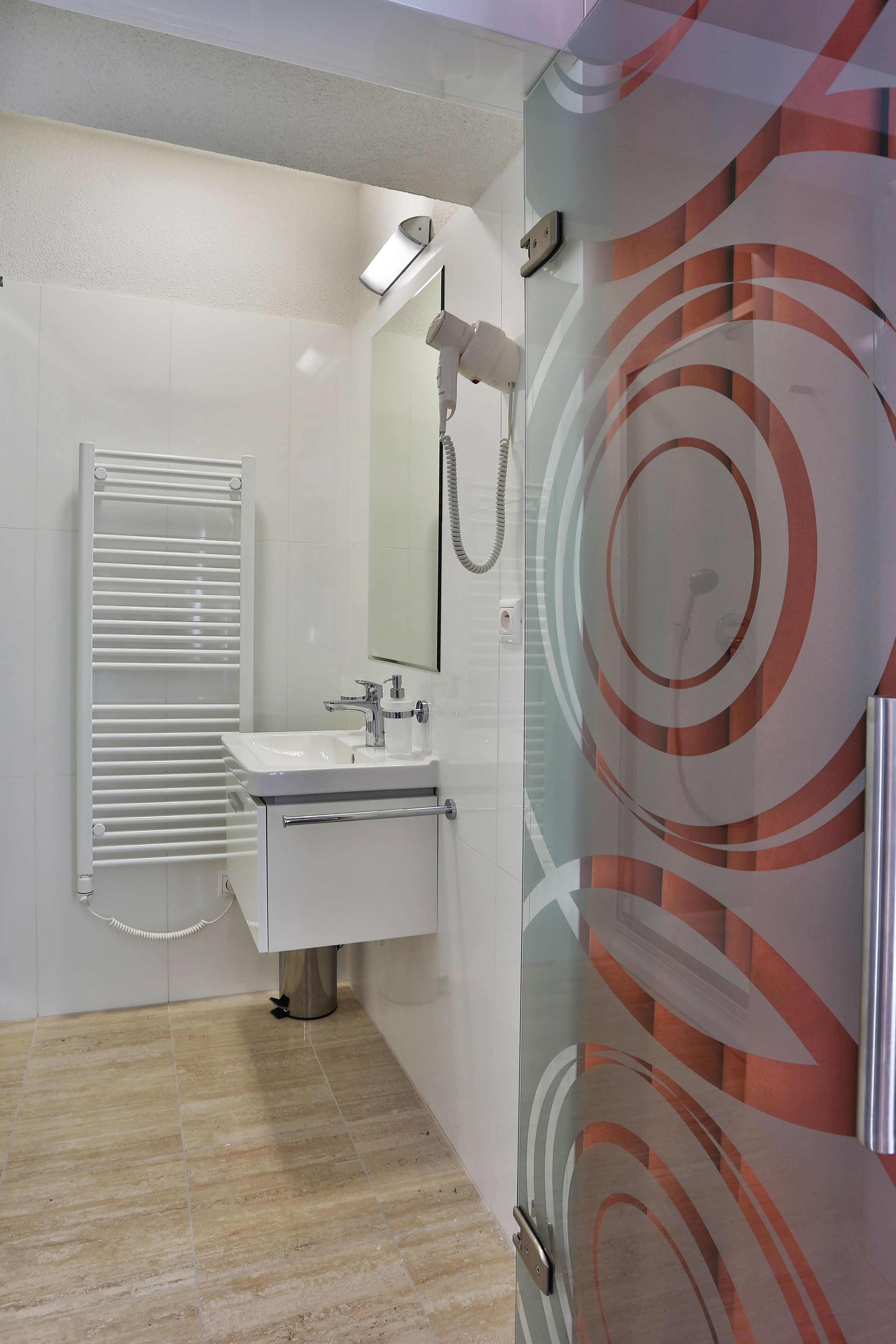 Un baño moderno con lavamanos blanco, espejo y perchero.