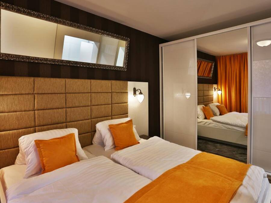 A hotel room with two beds, a large mirror, and a sliding door closet.