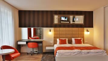 A hotel room with a bed, a desk, a chair, and a large mirror.