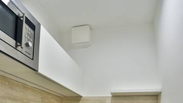 Uma cozinha compacta com micro-ondas integrado, pia e máquina de lavar louça.