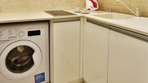Una cocina compacta con lavadora integrada, microondas y fregadero.