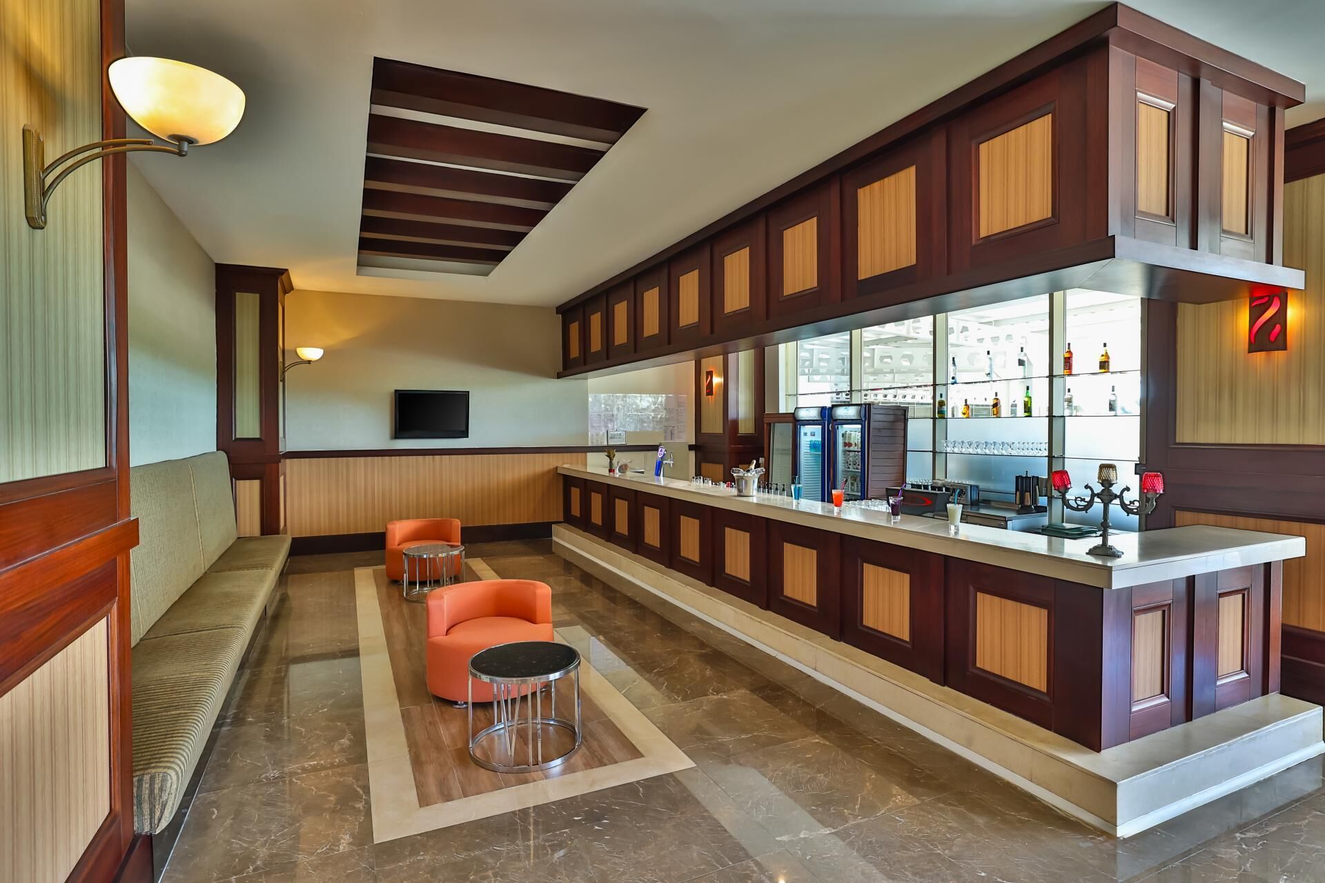 A bar area with a long counter, seating, and a television.