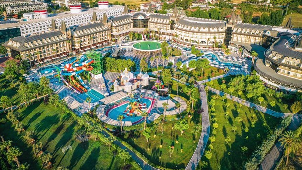An aerial view of a resort with multiple swimming pools, water slides, and a castle-like structure. - Crystal Prestige Pearl Collection - All inclusive (Kemer)