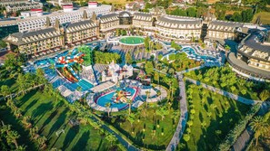 An aerial view of a resort with multiple swimming pools, water slides, and a castle-like structure. - Crystal Prestige Pearl Collection - All inclusive (Kemer)