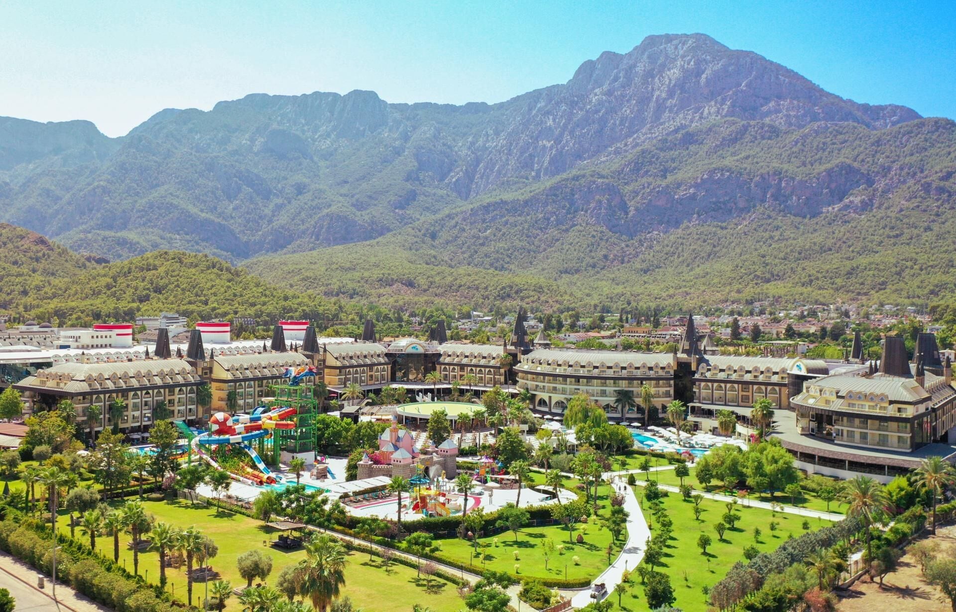 A resort with multiple buildings, a central pool area, and a mountainous backdrop.