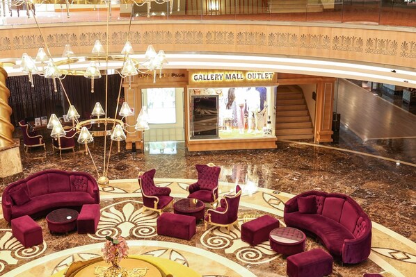 A lobby with a Gallery Mall Outlet, plush seating, a chandelier, and a marble floor.