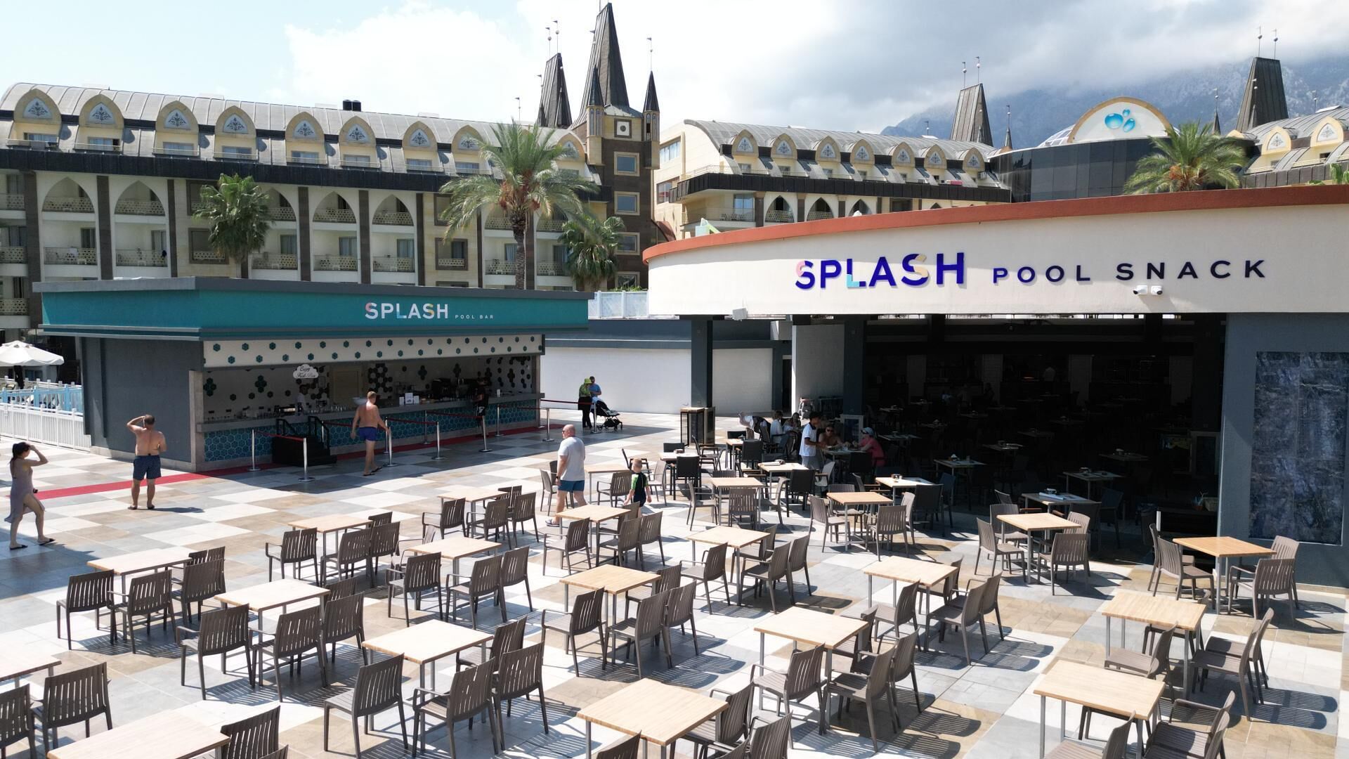 An outdoor seating area with tables and chairs, a pool bar, and a pool snack bar.