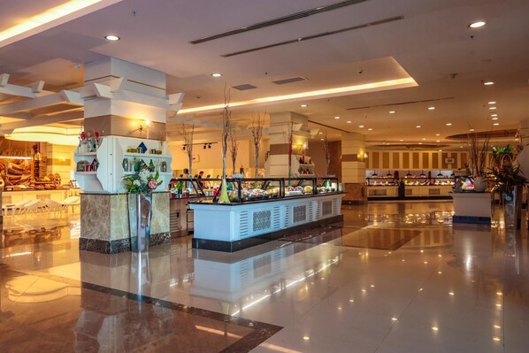 A modern hotel lobby with a central buffet, marble flooring, and decorative lighting.