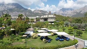 A resort with a pool area, lounge chairs, and a view of mountains. - Crystal Prestige Pearl Collection - All inclusive (Kemer)