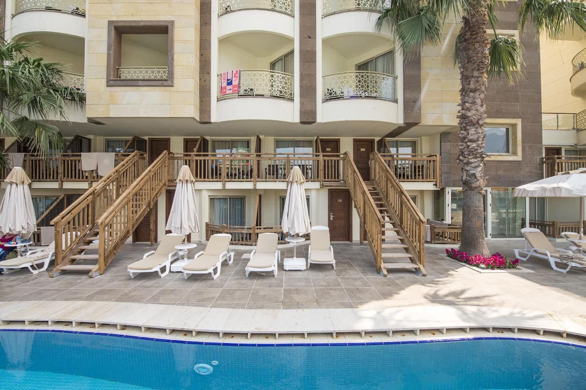 A hotel with a pool, lounge chairs, and a staircase leading to the upper floors.