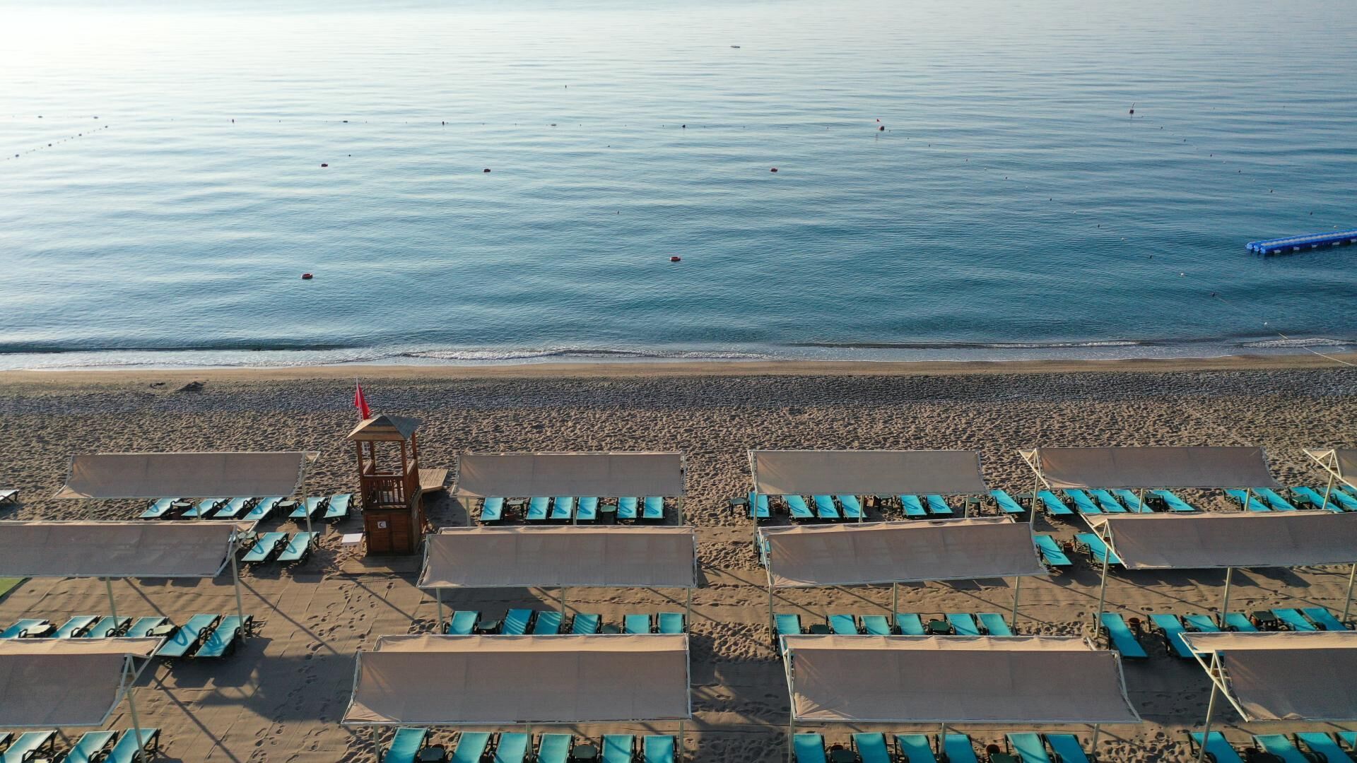 A beach with rows of sun loungers and a lifeguard tower.