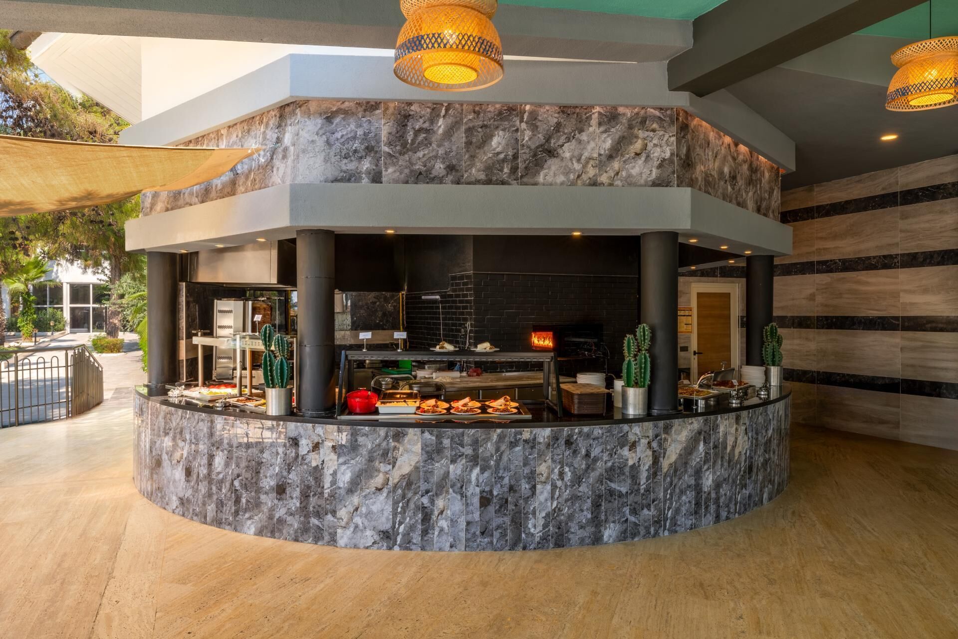 A modern kitchen area with a marble countertop, a brick wall, and a built-in oven.