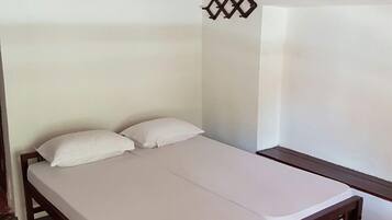 A small, single-bed room with a wooden frame and a white mattress.