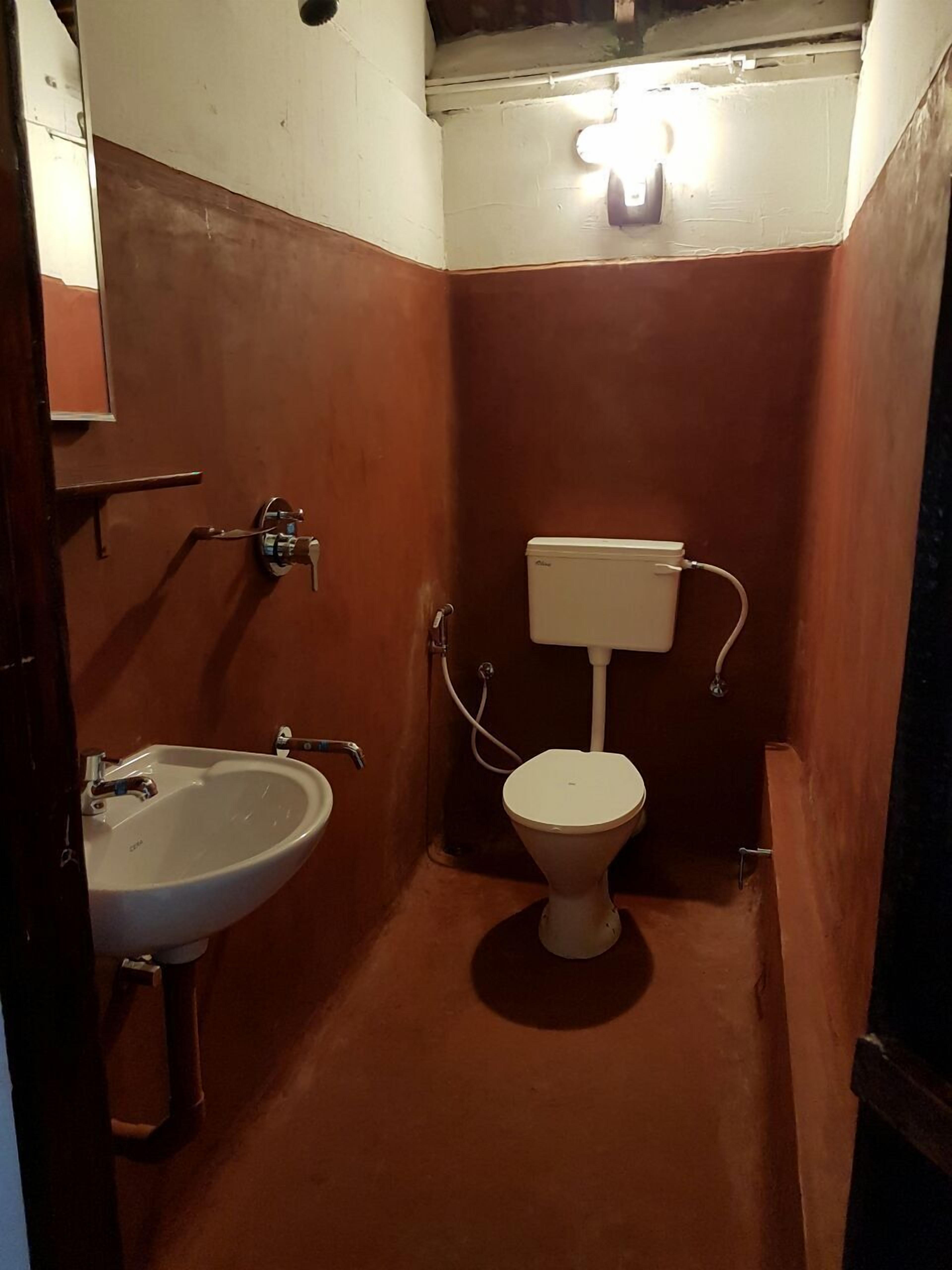 A small, narrow bathroom with a white sink and toilet.