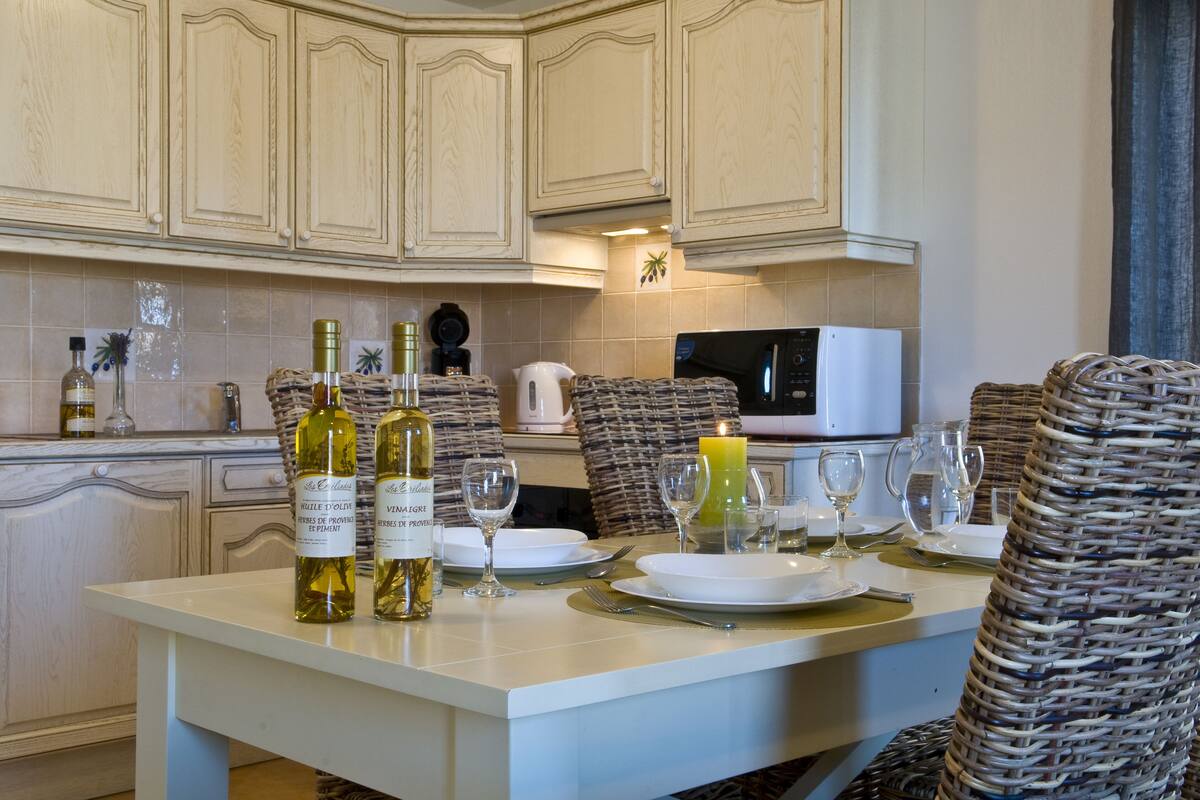 A dining area with a white table set for four, featuring wine bottles, glasses, and a candle.