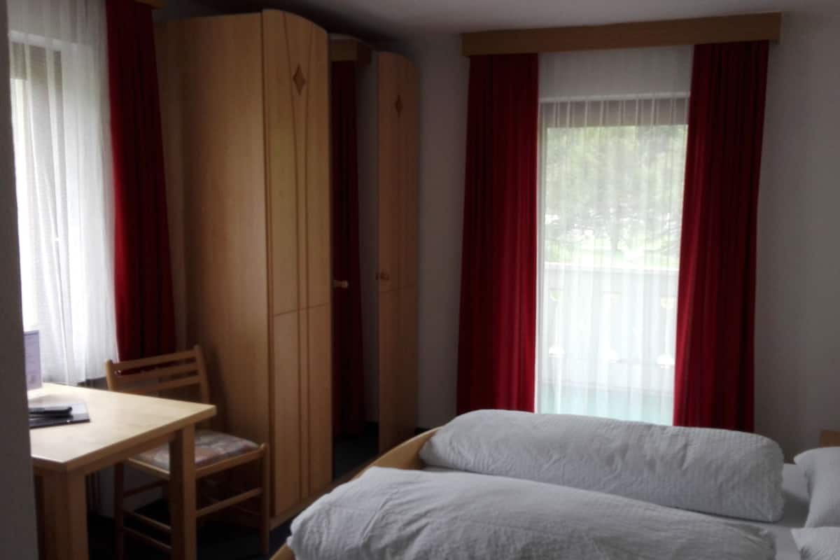 A room with a bed, a desk, and a wardrobe.